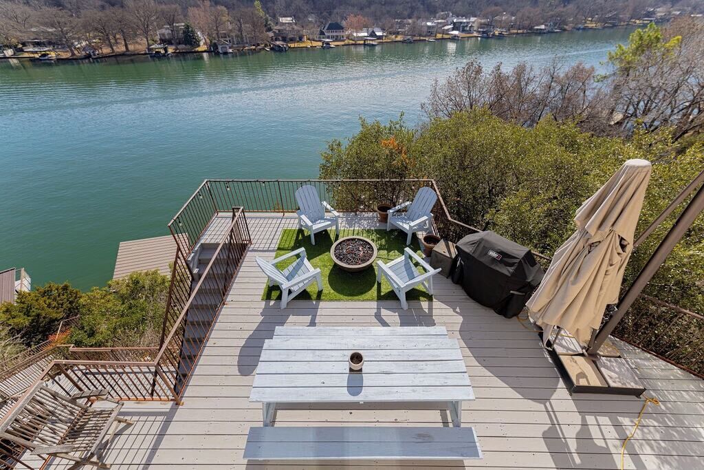 A deck with outdoor seating, a fire pit, and a view of a lake.