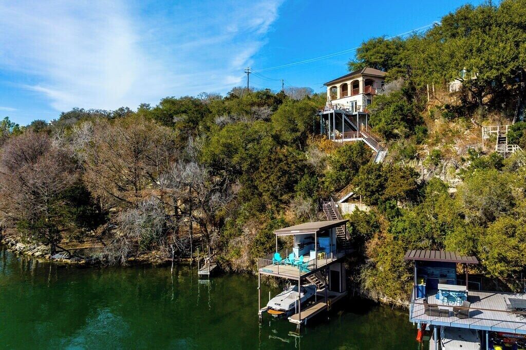 A house with a dock extending into a lake, surrounded by trees.