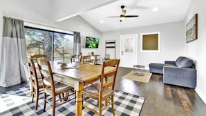 A spacious living area with a dining table, chairs, a sofa, and a ceiling fan.