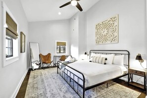 Une chambre à coucher avec un lit, un bureau, une chaise et un ventilateur de plafond.