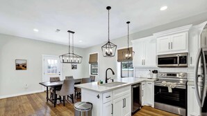 A modern kitchen with white cabinetry, stainless steel appliances, and a central island.