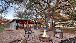 An outdoor patio area with a fire pit, metal chairs, and a covered seating area.