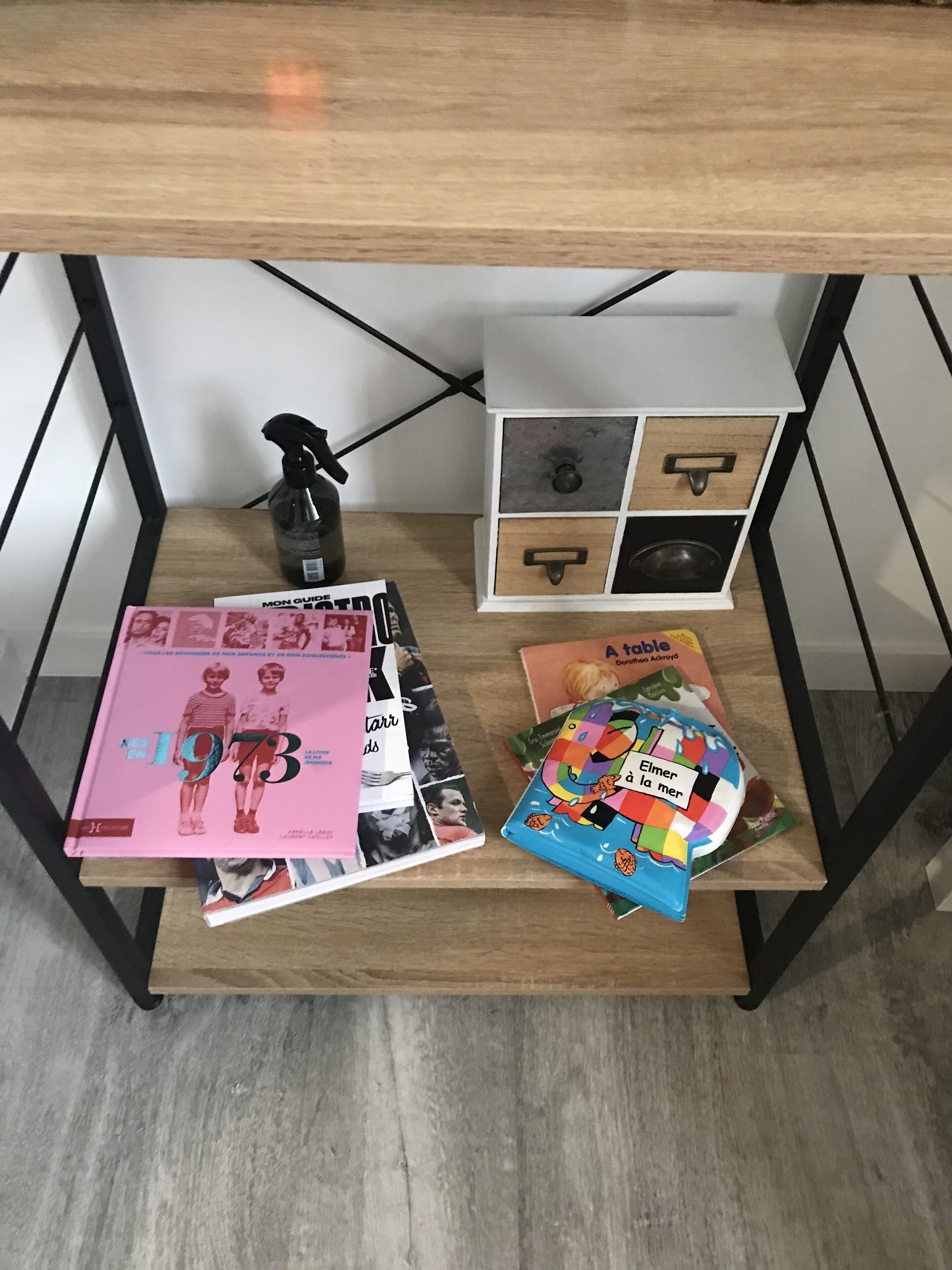 A wooden table with magazines, a spray bottle, and a small toy.