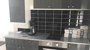 A modern kitchen with dark cabinetry, a built-in oven, and a coffee maker on the countertop. - residence romi entire accommodation 4 people (Tillé)