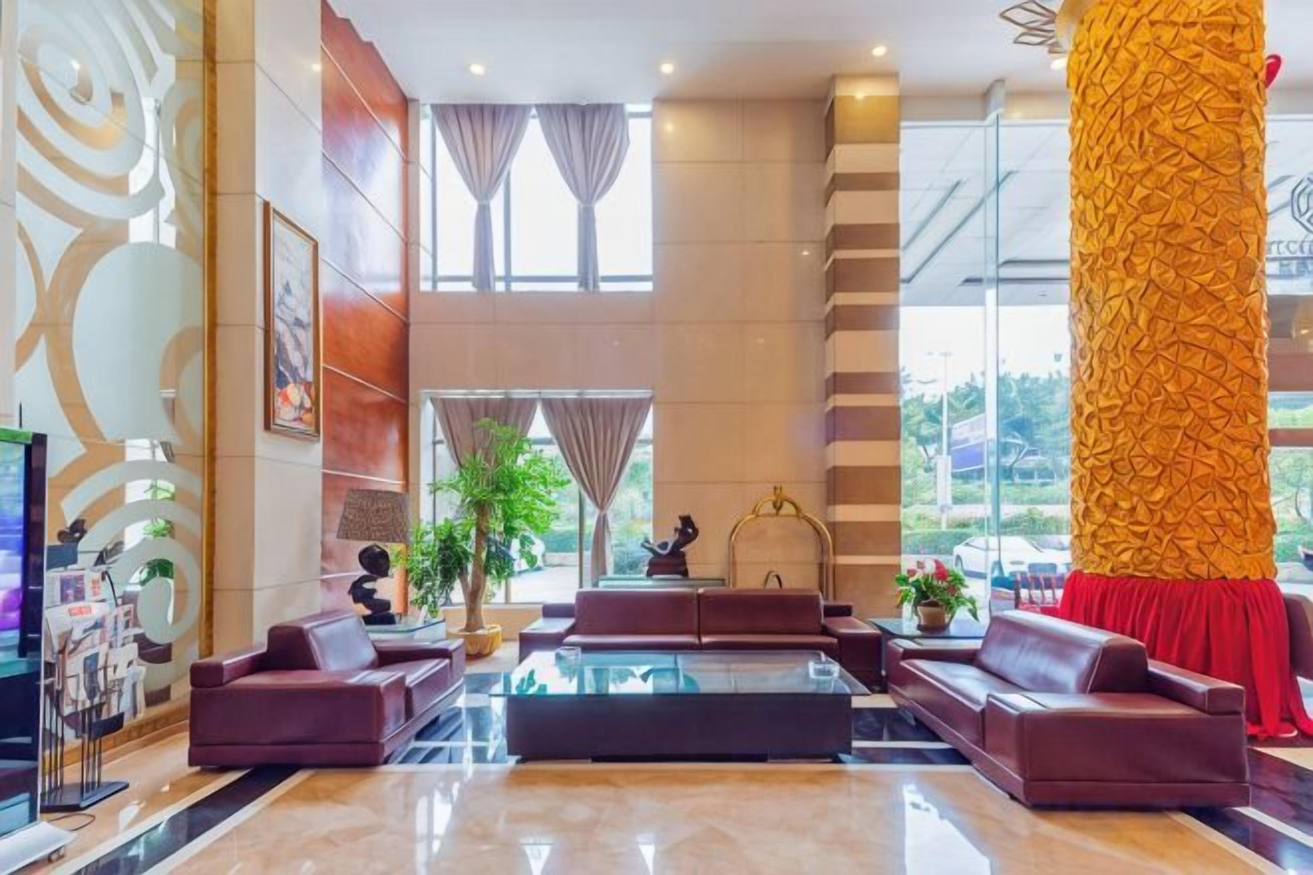 A spacious lobby with a large central seating area, a reception desk, and a staircase leading to upper floors.