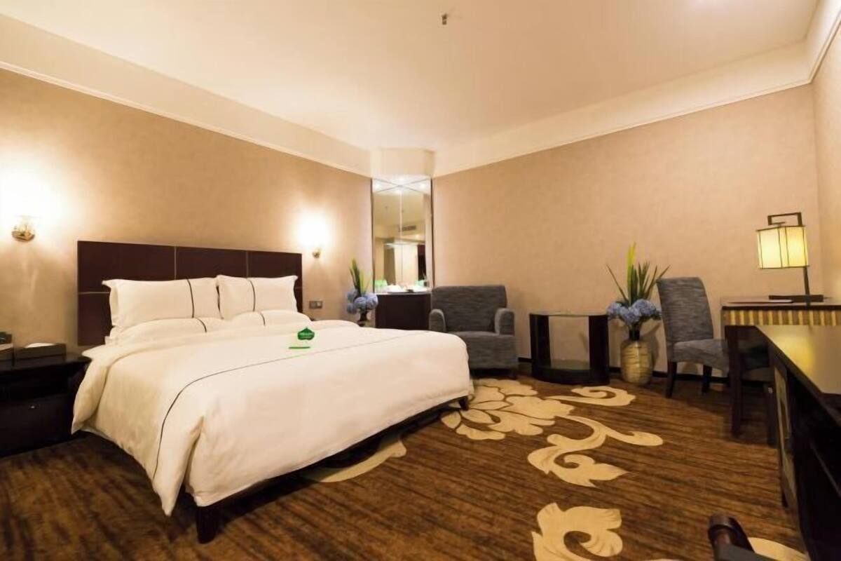 Una habitación de hotel con una cama, un escritorio, una silla y una mesita.