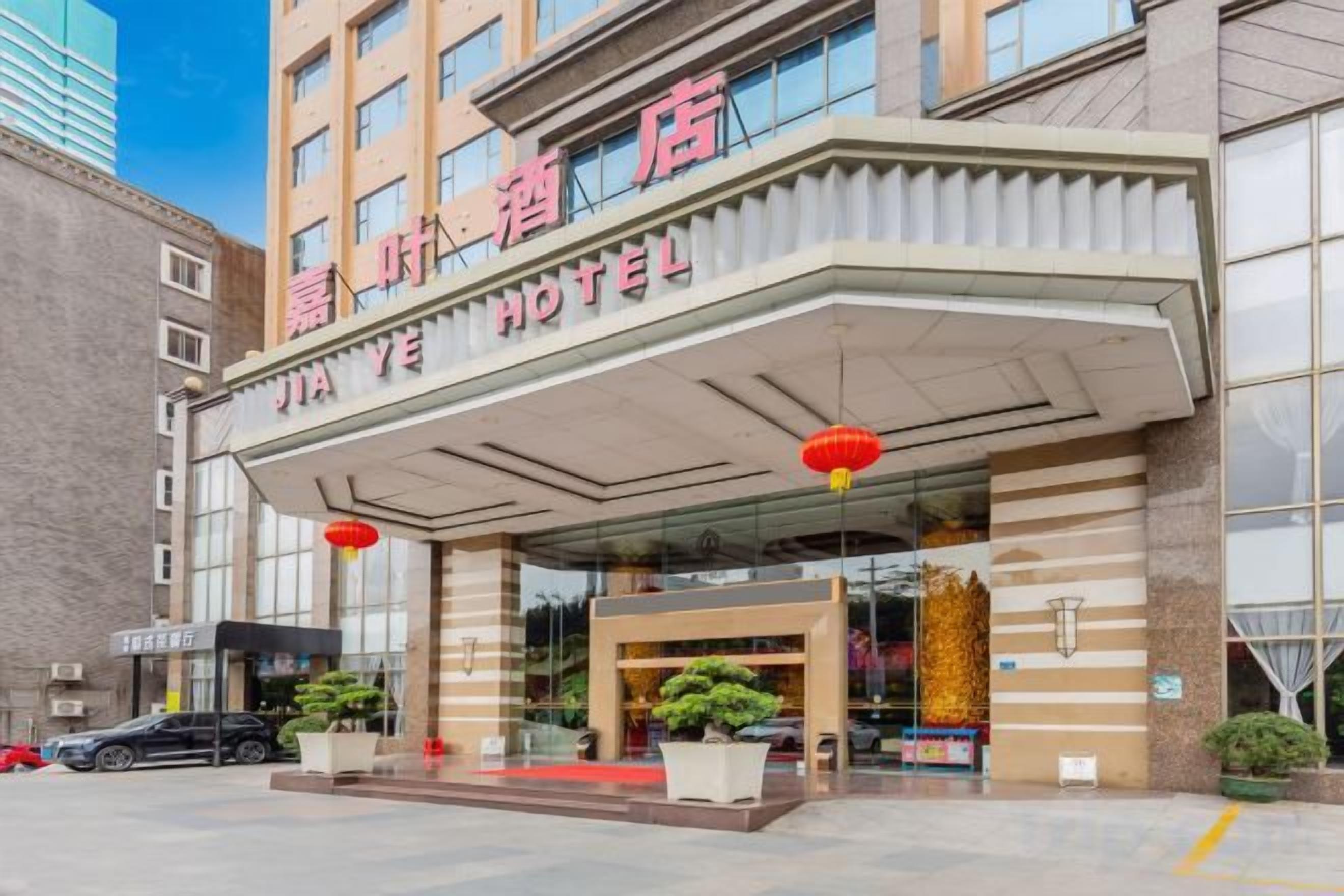 A hotel entrance with a covered entrance, large windows, and red lanterns.