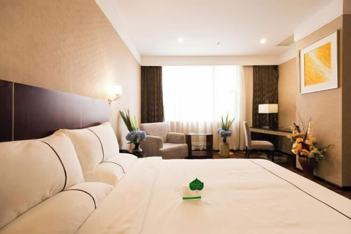 Una habitación de hotel con cama, sofá, escritorio y una silla.
