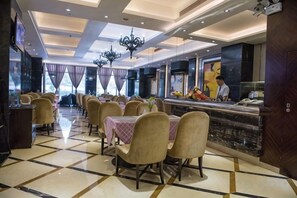 Um restaurante com um balcão comprido, várias mesas e cadeiras.