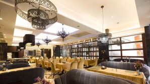 Un restaurante espacioso con techos altos, candelabros ornamentales y un diseño de interiores moderno.
