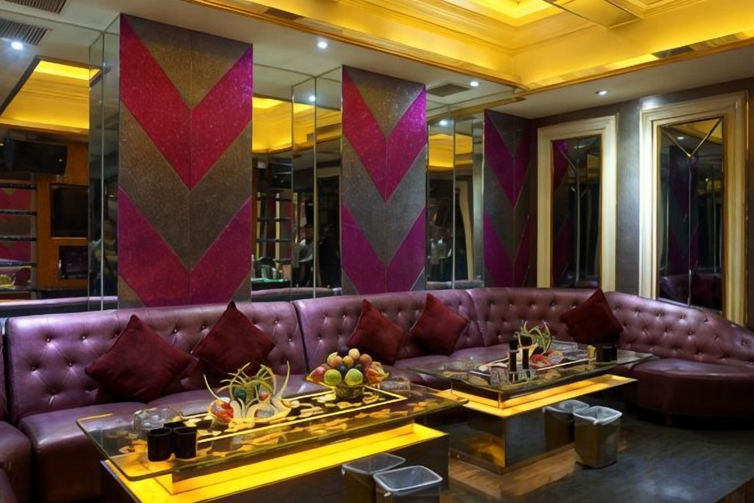 A modern lounge area with a leather sofa, a coffee table with decorative items, and mirrored walls.