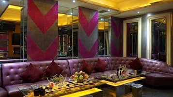 A modern lounge area with a leather sofa, a coffee table with decorative items, and mirrored walls.