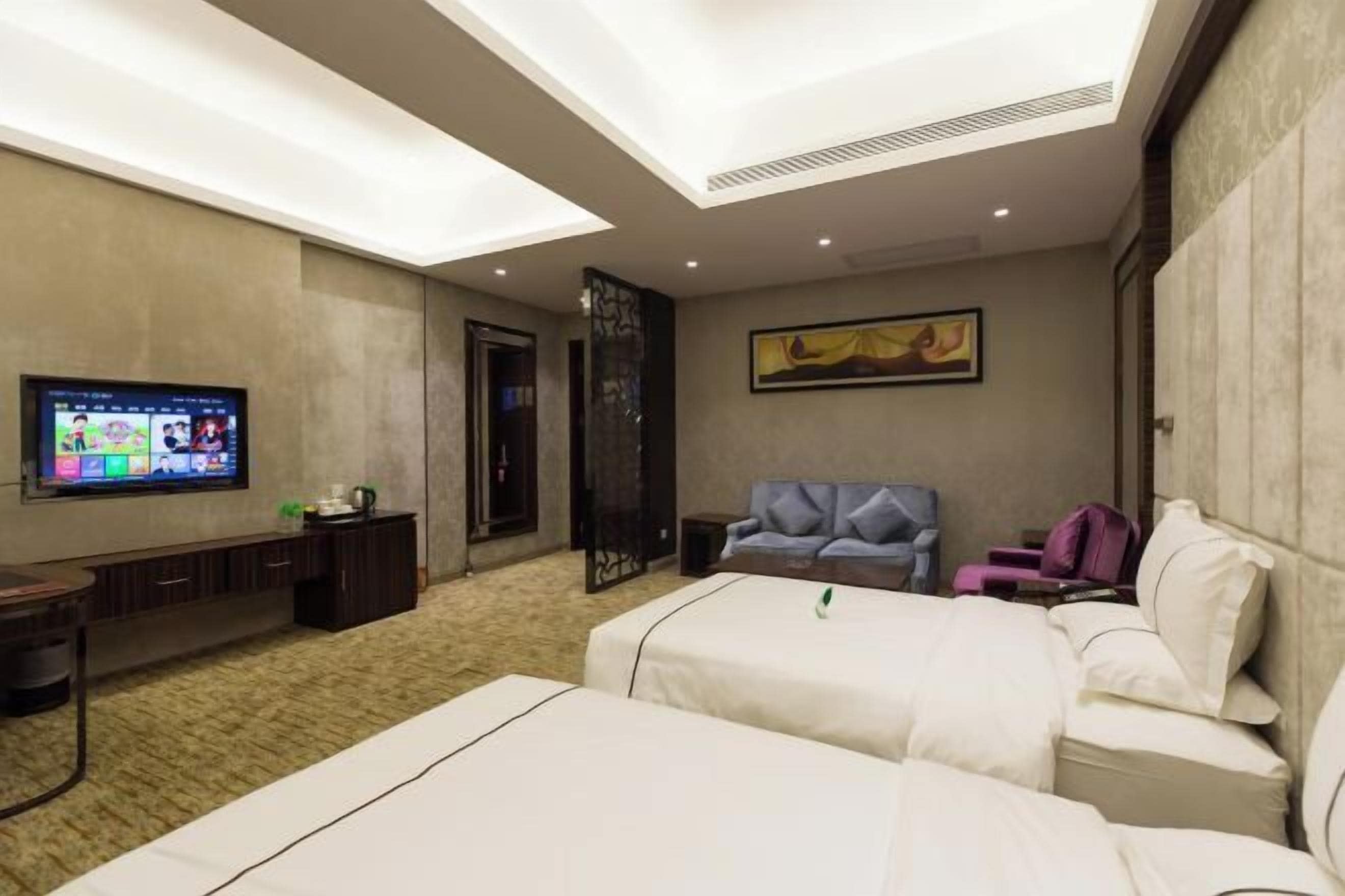 Ein Hotelzimmer mit einem großen Bett, einer Couch, einem Fernseher und einem Gemälde an der Wand.