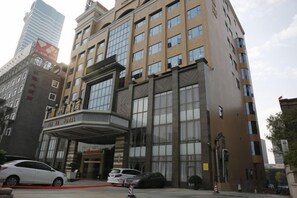 Un hotel con una entrada destacada, varios pisos y un diseño arquitectónico moderno.
