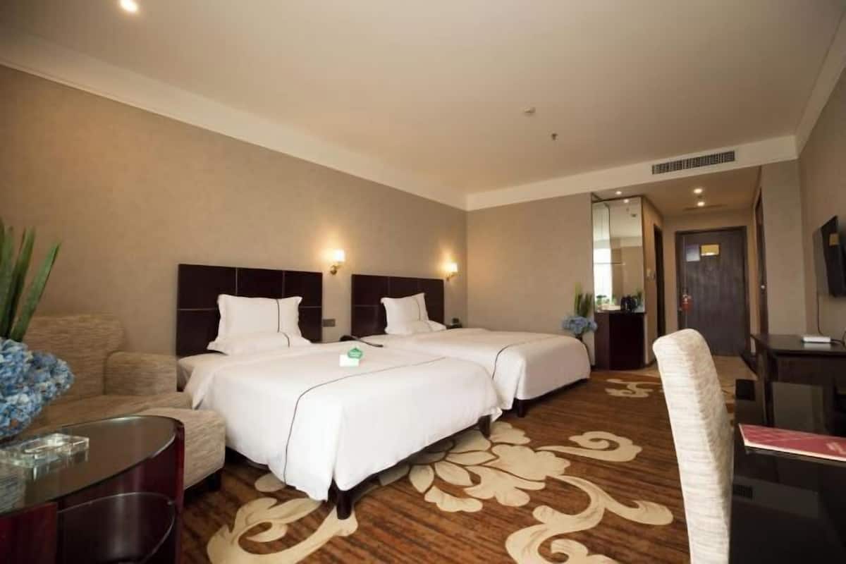 Una habitación de hotel con dos camas, un sofá, una mesita y un espejo.