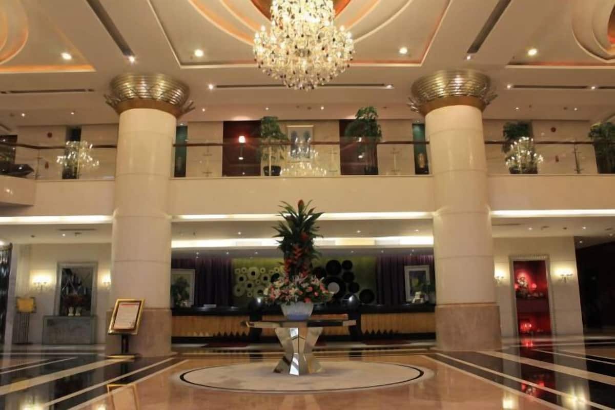 Un vestíbulo con una recepción central, una araña de cristal y un área de descanso circular.