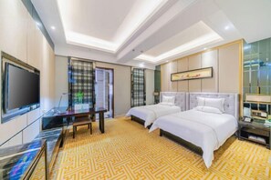 A hotel room with two beds, a desk, a TV, and a patterned carpet. - Jia Ye Hotel (Dongguan)