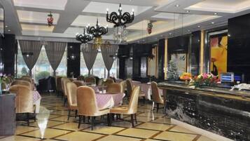 A hotel dining area with tables, chairs, a chandelier, and a decorative fountain.