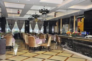 Un comedor de hotel con mesas, sillas, una araña y una fuente decorativa.