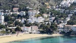 Un pueblo costero con edificios construidos en una ladera con vista a una playa.