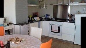 Una cocina compacta con comedor, que incluye una mesa con sillas, un refrigerador, un horno y un microondas.