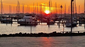 Marina com barcos atracados, céu claro e pôr do sol.