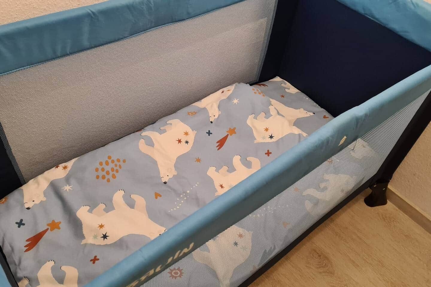 Un berceau avec un matelas gris orné d’un motif représentant un ours polaire.