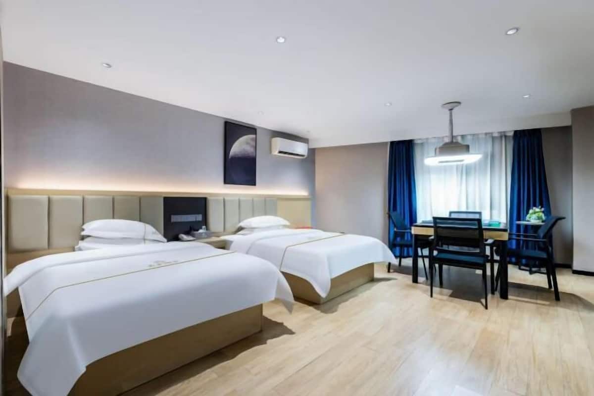 A hotel room with two beds, a desk, and a chair.