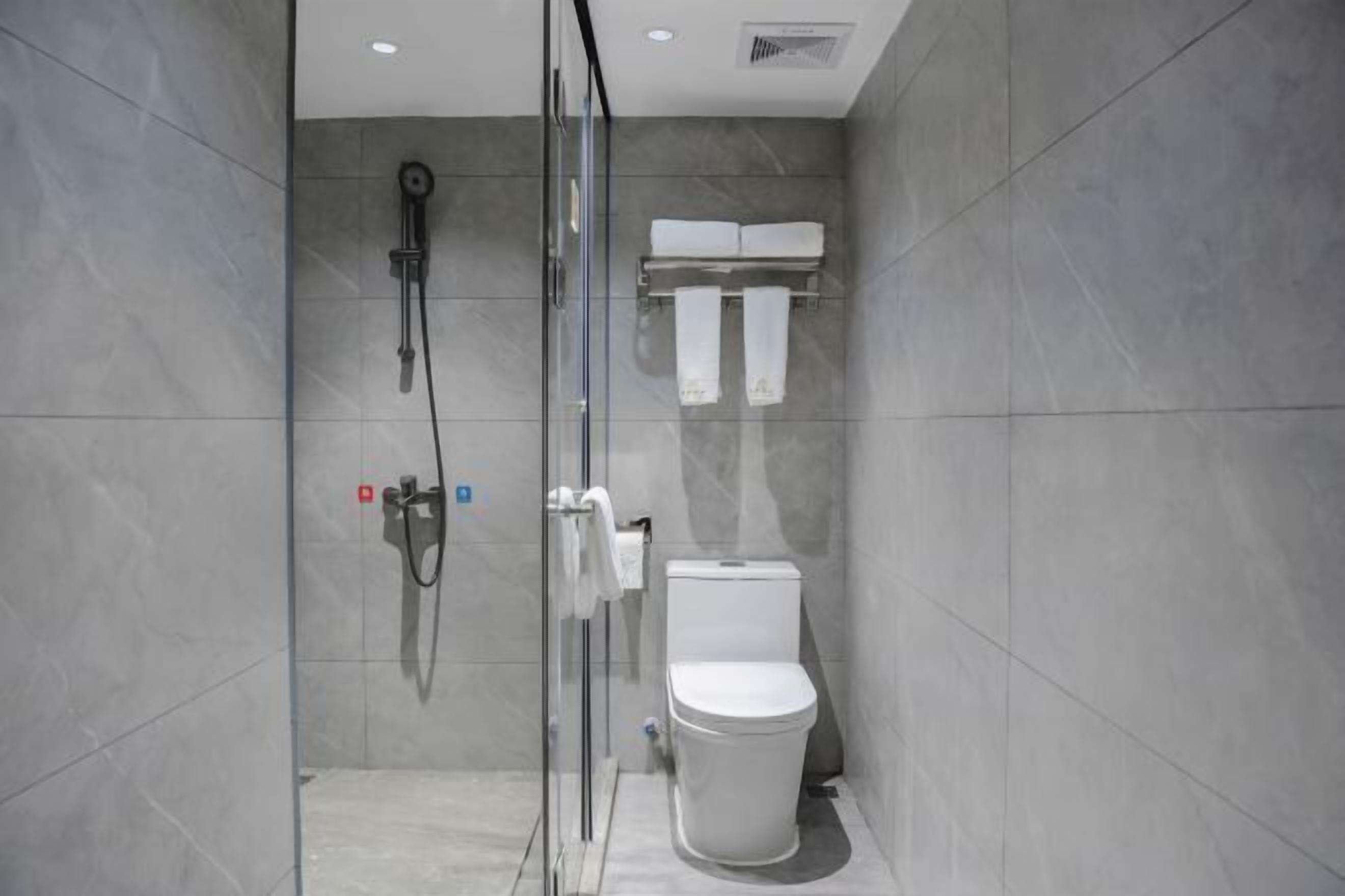 A modern bathroom with a glass-enclosed shower, a toilet, and a towel rack.