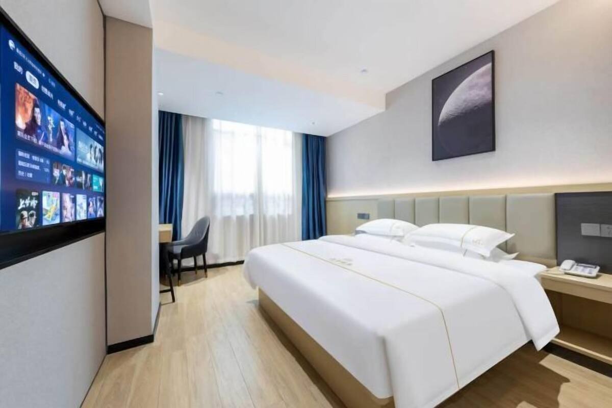 A hotel room with a large bed, a desk, a flat-screen TV, and a wall-mounted artwork.