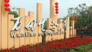 A sign for Wantian Ecological Park with a wooden fence and red lanterns.