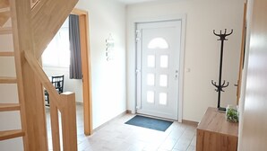 Eine Treppe führt zu einem Raum mit einer weißen Tür, einem Kleiderständer und einem kleinen Tisch mit einem Glasbehälter.
