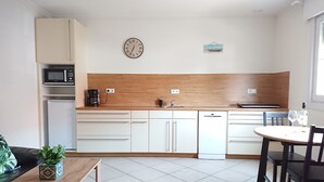 Eine moderne Küche mit weißen Schränken, einer Mikrowelle, einer Kaffeemaschine und einer Uhr an der Wand.