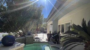 A swimming pool with a tiled deck, surrounded by palm trees and a building with a tiled roof. - Southshore single story Tuscany style home for rent! (Henderson)