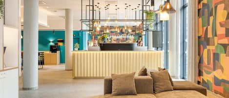 A modern lobby with a reception desk, seating area, and a colorful wall.
