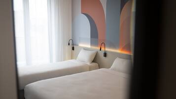 Een hotelkamer met twee bedden, een groot raam met witte gordijnen, en een muur met abstracte kunst.