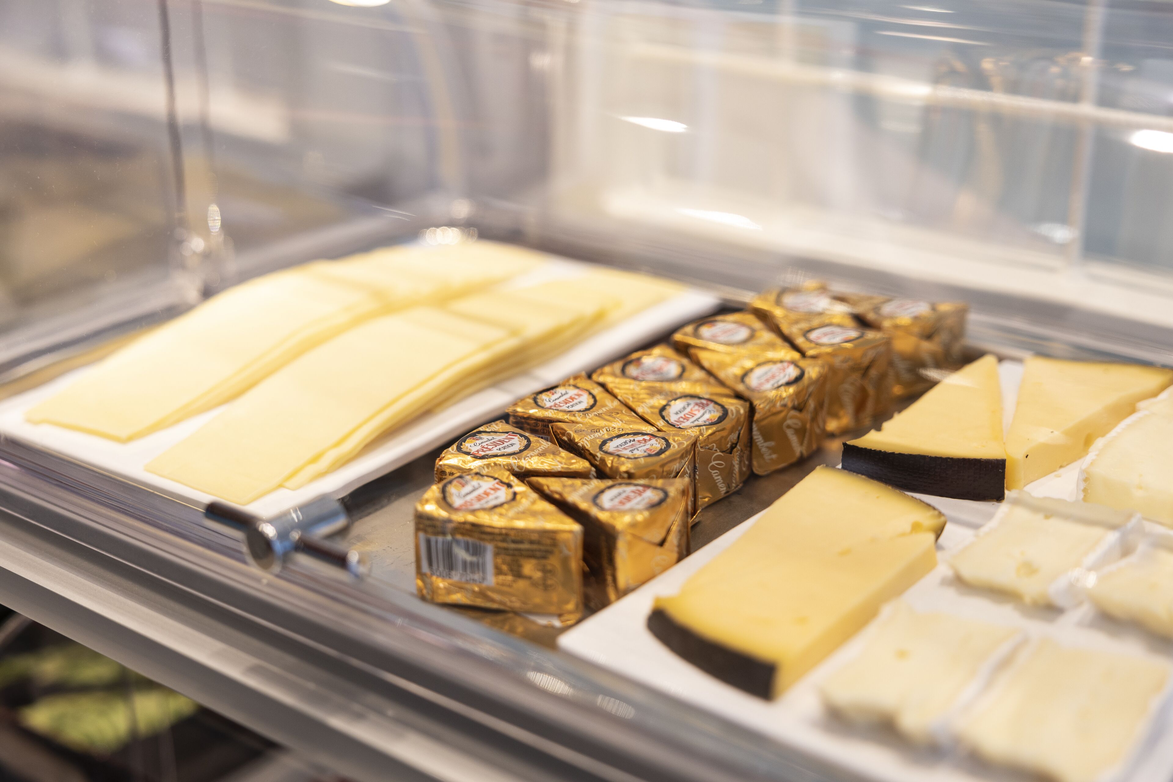 A display case with various types of cheese and chocolate bars.