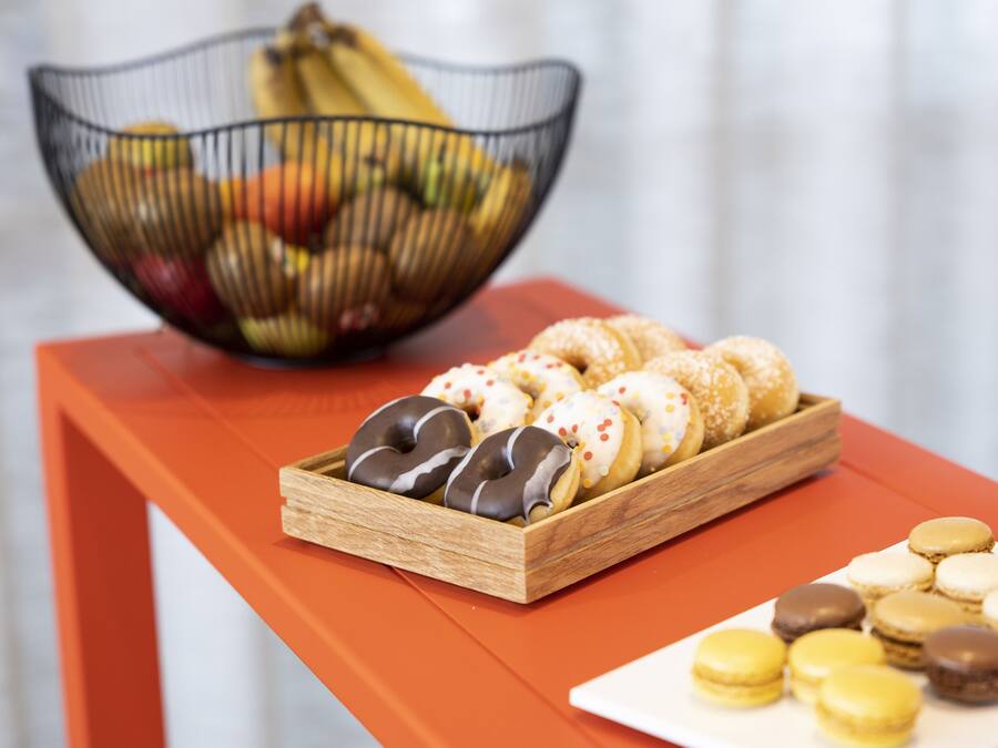 Ein Tisch mit Obstschale und Tabletts mit Donuts und Macarons.