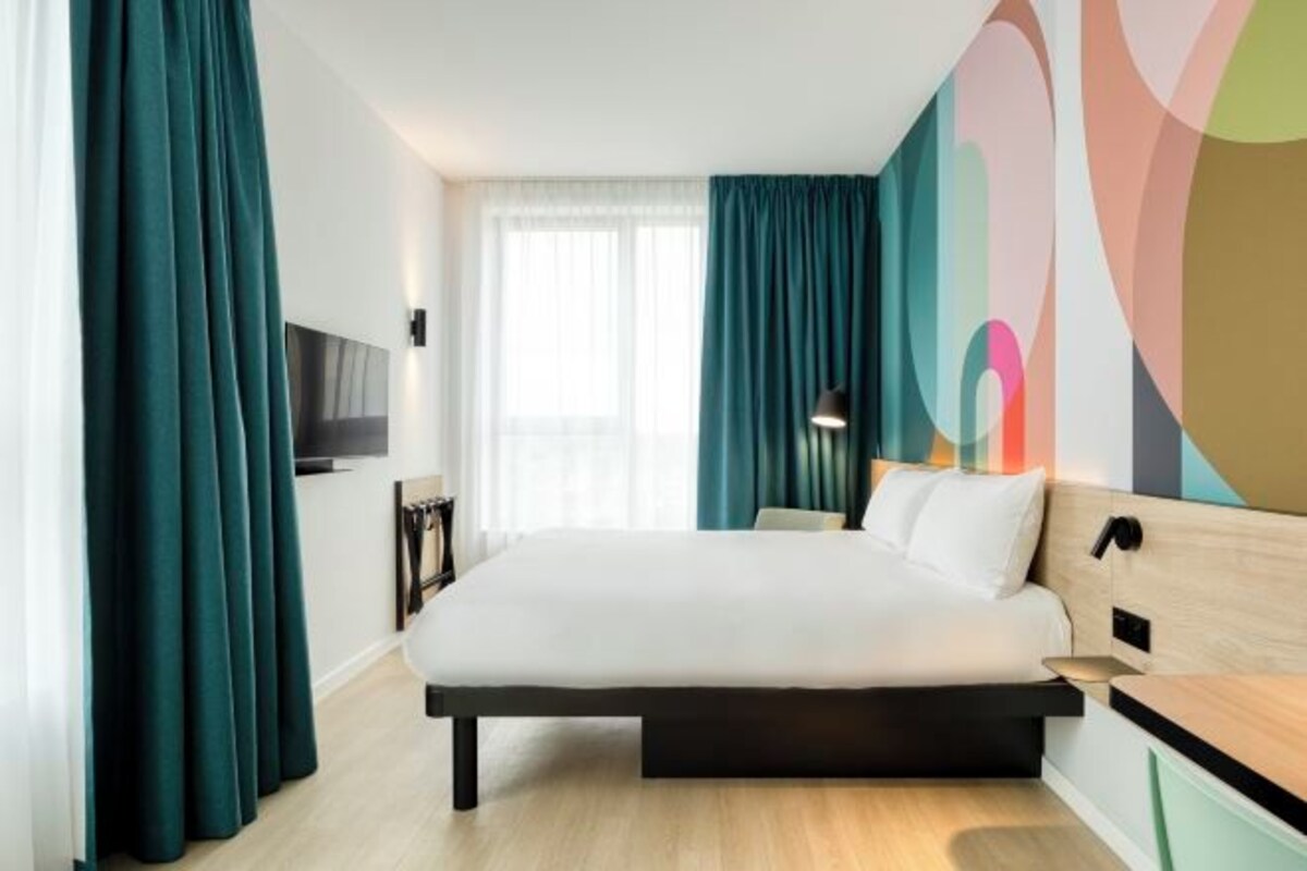 Una habitación de hotel moderna con una cama grande, un escritorio y un televisor.