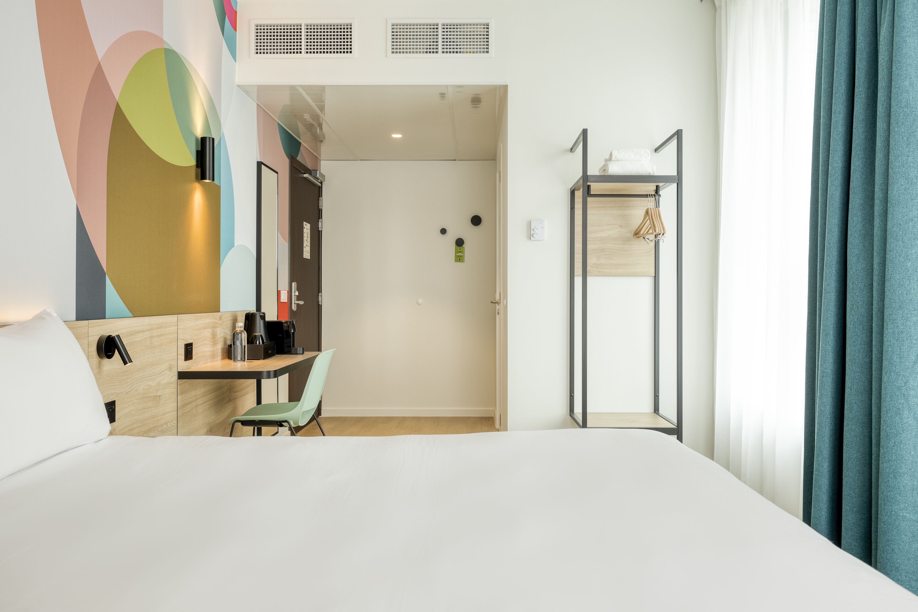 Une chambre d’hôtel avec un lit, un bureau, une chaise, une armoire et une porte de salle de bain.
