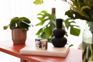 A book titled 'MAISONS de FAMILLES' on a red surface with a potted plant, a black vase, and two patterned cups. - B&B HOTEL Mechelen (Mechelen)