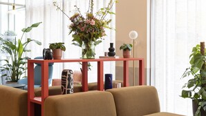Una sala de estar moderna con un sofá seccional, una consola roja y un jarrón con flores.