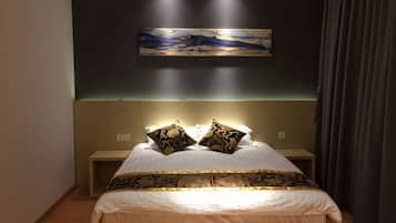 A bedroom with a bed, two bedside tables, a headboard, and a wall-mounted artwork.