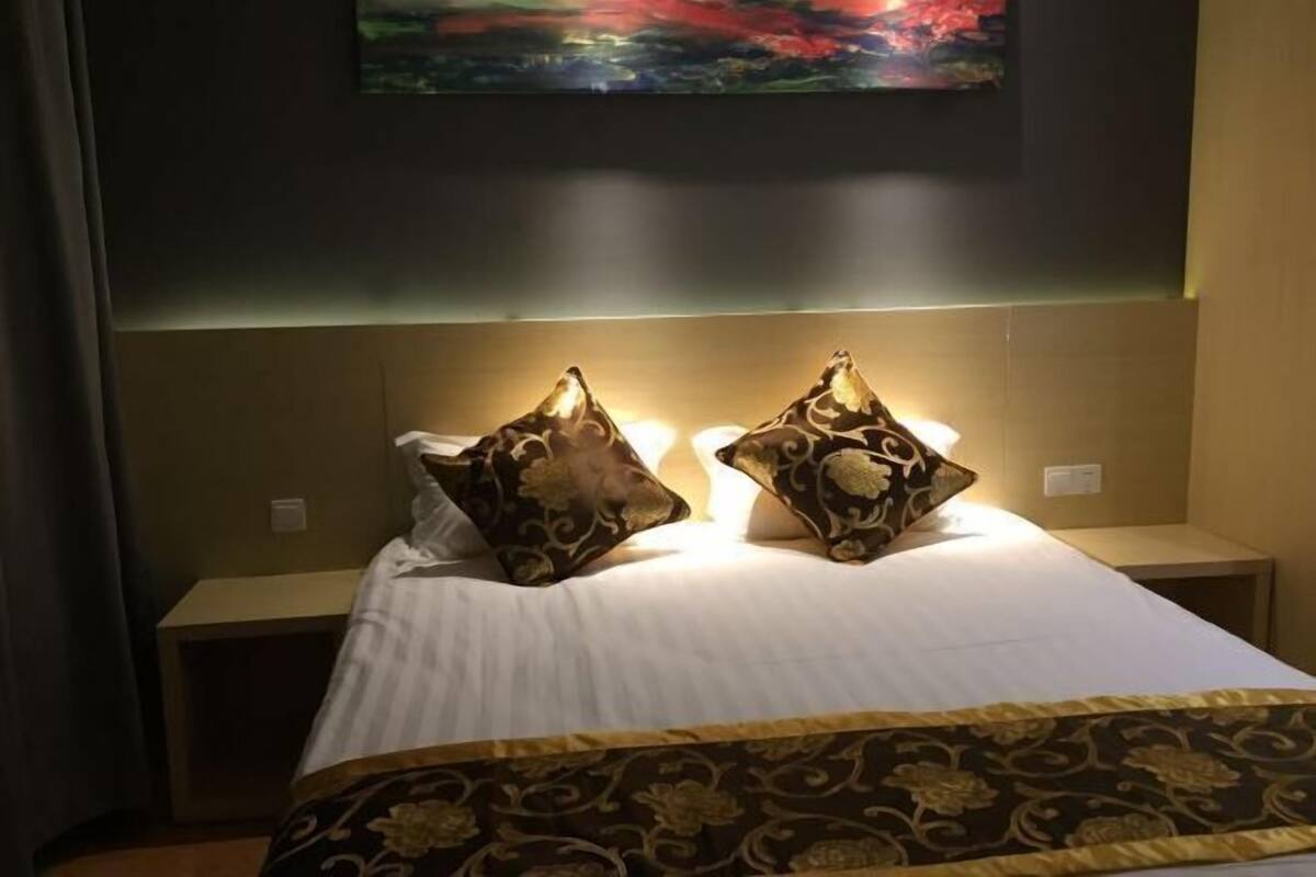 Una habitación de hotel con una cama, dos mesitas de noche y un cuadro en la pared.