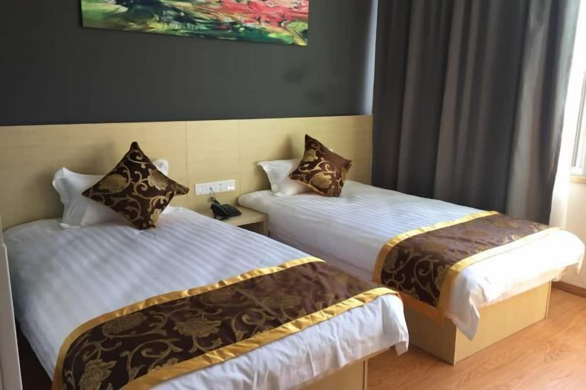 Habitación de hotel con dos camas, cada una con una colcha estampada y almohadas a juego.