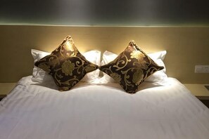 A bed with white linens and two decorative pillows. - Juzi Select Hotel (Shanghai)