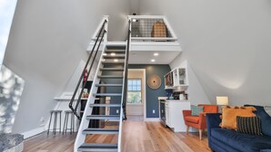 Un moderno appartamento in stile loft con una scala centrale, un angolo cottura, un soggiorno con divano blu e un'area pranzo.