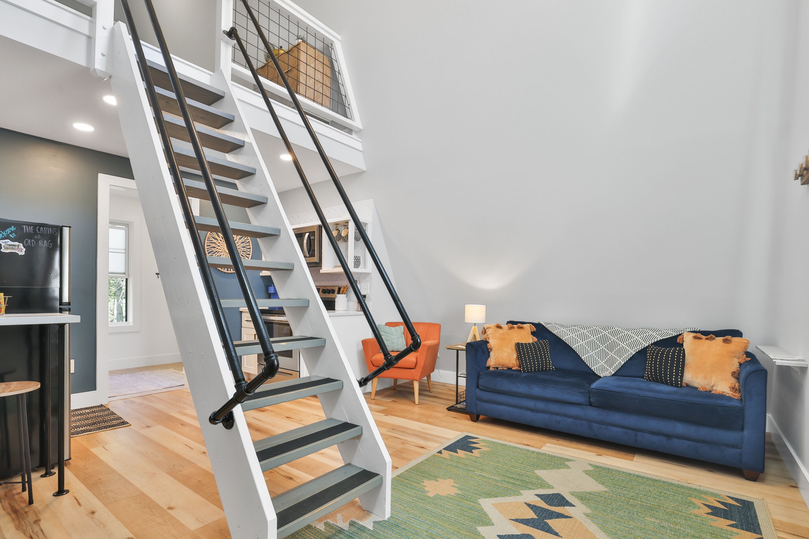 Un interior moderno con una escalera, un sofá azul y un comedor.