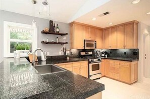 Enjoy cooking in this well-equipped kitchen with a double sink, microwave, oven, and stovetop.