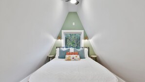 Une chambre à coucher avec un lit, des oreillers, une fenêtre et des lampes de chevet.